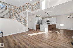 Unfurnished living room with a towering ceiling, a chandelier, light wood-type flooring, stairs, and recessed lighting - 