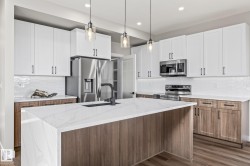 Kitchen featuring tasteful backsplash, pendant lighting, stainless steel appliances, light stone countertops, and brown cabinetry - 