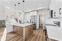 Kitchen with brown cabinetry, stainless steel appliances, light stone counters, tasteful backsplash, and a center island with sink - 