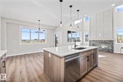 Kitchen with dishwasher, decorative light fixtures, light stone counters, and light wood-style floors - 