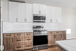Kitchen with appliances with stainless steel finishes, light stone counters, white cabinetry, tasteful backsplash, and light wood finished floors - 