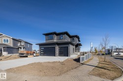 View of front of property featuring a garage, concrete driveway, and stone siding - 