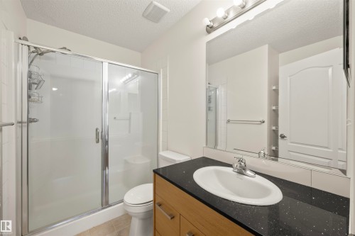 Full bath with a stall shower, vanity, a textured ceiling, and light tile patterned floors - 2209 7343 South Terwillegar Drive, Edmonton, AB - Indoor Photo Showing Bathroom