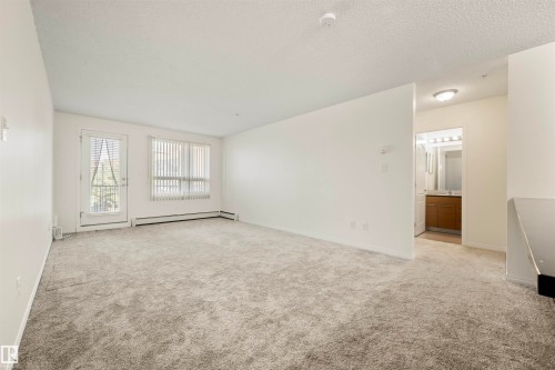 Spare room featuring light carpet, a textured ceiling, and a baseboard radiator - 2209 7343 South Terwillegar Drive, Edmonton, AB - Indoor Photo Showing Other Room