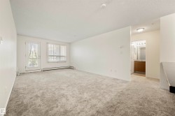 Spare room featuring light carpet, a textured ceiling, and a baseboard radiator - 