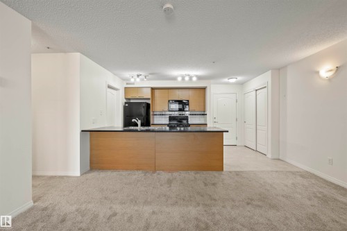 Kitchen featuring dark countertops, tasteful backsplash, a peninsula, light carpet, and black appliances - 2209 7343 South Terwillegar Drive, Edmonton, AB - Indoor Photo Showing Kitchen
