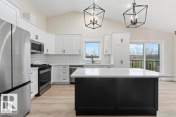 Kitchen featuring dark cabinets, vaulted ceiling, appliances with stainless steel finishes, decorative backsplash, and pendant lighting - 