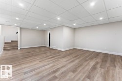 Finished below grade area featuring light wood-type flooring, stairs, and recessed lighting - 