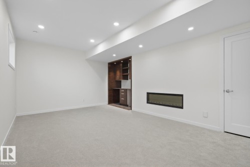 Below grade area featuring a glass covered fireplace, recessed lighting, and light carpet - 14502 103 Avenue, Edmonton, AB - Indoor