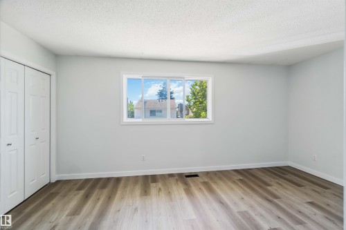 Unfurnished bedroom with a textured ceiling, a closet, and light wood-style floors - 1096 Millbourne Road E, Edmonton, AB - Indoor Photo Showing Other Room