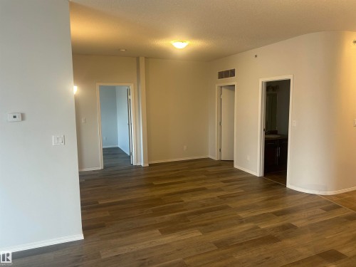 Empty room with dark wood-style flooring and a textured ceiling - 411 4316 139 Avenue, Edmonton, AB - Indoor Photo Showing Other Room