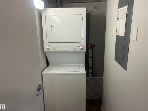 Washroom featuring electric panel, stacked washing machine and dryer, and tile patterned flooring - 411 4316 139 Avenue, Edmonton, AB - Indoor Photo Showing Laundry Room