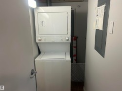 Washroom featuring electric panel, stacked washing machine and dryer, and tile patterned flooring - 