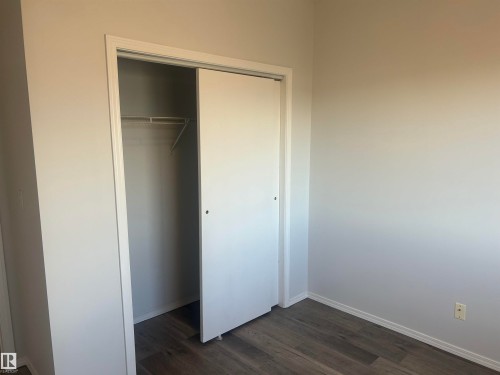 Unfurnished bedroom featuring dark wood finished floors and a closet - 411 4316 139 Avenue, Edmonton, AB - Indoor Photo Showing Other Room