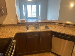 Kitchen with appliances with stainless steel finishes, dark brown cabinetry, a peninsula, open floor plan, and dark stone counters - 
