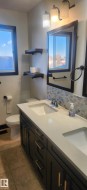 Bathroom with double vanity, decorative backsplash, and light tile patterned floors - 