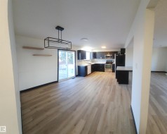 Kitchen with light countertops, light wood-style floors, stainless steel appliances, decorative backsplash, and open floor plan - 