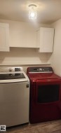 Laundry area with independent washer and dryer, cabinet space, and wood finished floors - 