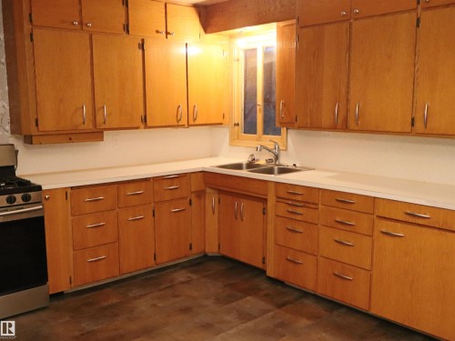 Kitchen featuring stainless steel range with gas cooktop, light countertops, brown cabinetry, and dark wood-type flooring - 4032A Twp Rd 604, Rural Barrhead County, AB - Indoor Photo Showing Kitchen With Double Sink