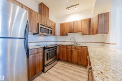 Kitchen featuring stainless steel appliances, light stone counters, brown cabinets, tasteful backsplash, and a textured ceiling - 