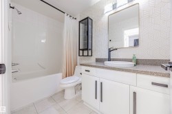 Bathroom featuring vanity, shower / bath combination with curtain, light tile patterned floors, and tile walls - 