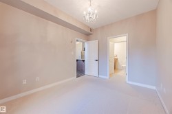 Unfurnished bedroom featuring light carpet, a chandelier, and connected bathroom - 