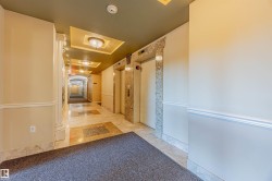 Hallway featuring a tray ceiling, elevator, and light tile patterned flooring - 