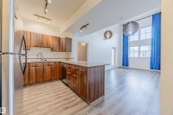 Kitchen with stainless steel appliances, light stone counters, brown cabinets, light wood-type flooring, and a peninsula - 