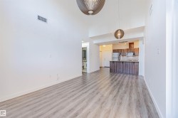 Unfurnished living room featuring light wood-style floors and a high ceiling - 