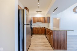 Kitchen featuring light stone counters, stainless steel appliances, light wood-style flooring, backsplash, and brown cabinetry - 