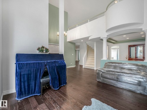 Living room with arched walkways, dark wood-style floors, stairs, a towering ceiling, and ornate columns - 316 Burton Road, Edmonton, AB - Indoor