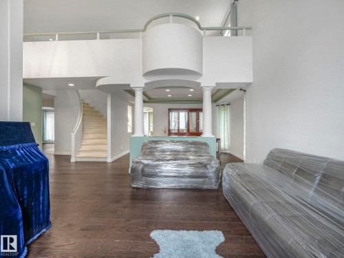Interior space with dark wood-type flooring, a high ceiling, stairway, recessed lighting, and decorative columns - 316 Burton Road, Edmonton, AB - Indoor Photo Showing Other Room