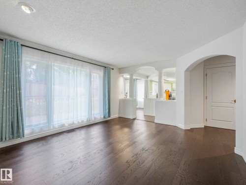 Unfurnished living room featuring a textured ceiling, dark wood finished floors, decorative columns, and arched walkways - 316 Burton Road, Edmonton, AB - Indoor Photo Showing Other Room