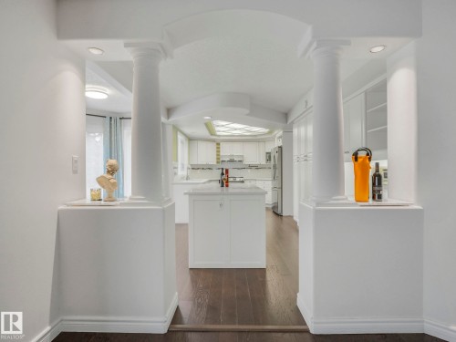 Kitchen featuring white cabinets, a kitchen island, dark wood-style flooring, freestanding refrigerator, and recessed lighting - 316 Burton Road, Edmonton, AB - Indoor Photo Showing Other Room