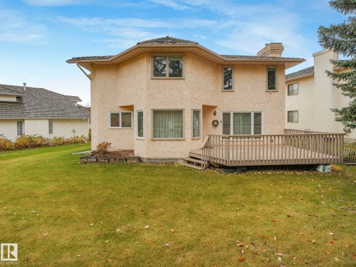 Back of property with a wooden deck, stucco siding, a yard, and a chimney - 316 Burton Road, Edmonton, AB - Outdoor