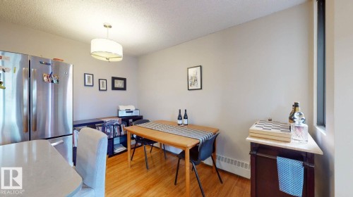 Dining room featuring a textured ceiling, light wood-type flooring, and a baseboard heating unit - 301 10175 109 Street, Edmonton, AB - Indoor Photo Showing Other Room