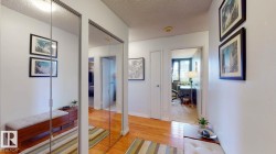 Corridor with a textured ceiling, light wood-style floors, and a desk - 