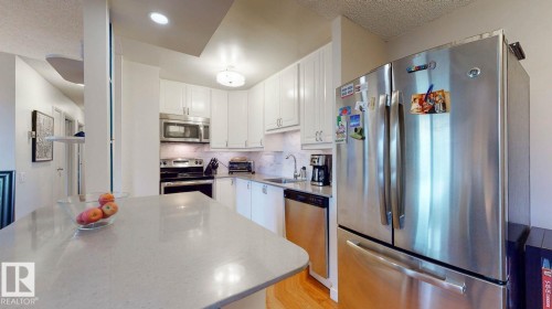 Kitchen with appliances with stainless steel finishes, tasteful backsplash, white cabinetry, and light wood finished floors - 301 10175 109 Street, Edmonton, AB - Indoor Photo Showing Kitchen With Upgraded Kitchen