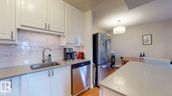 Kitchen with white cabinets, appliances with stainless steel finishes, decorative backsplash, a textured ceiling, and light stone countertops - 