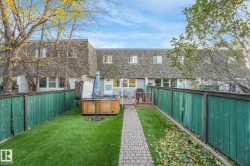 Rear view of house featuring mansard roof, a hot tub, a wooden deck, a fenced backyard, and a shingled roof - 