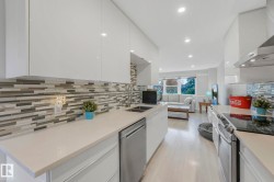 Kitchen featuring stainless steel appliances, white cabinetry, wall chimney range hood, modern cabinets, and recessed lighting - 