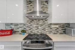 Kitchen with wall chimney range hood, stainless steel electric range oven, tasteful backsplash, and white cabinets - 