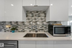 Kitchen with tasteful backsplash, appliances with stainless steel finishes, white cabinetry, light stone countertops, and recessed lighting - 