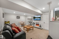 Living room featuring light colored carpet, a brick fireplace, recessed lighting, ornamental molding, and stairs - 
