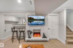 Living area featuring light carpet, ornamental molding, a brick fireplace, and stairs - 