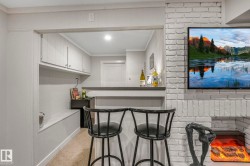 Indoor bar featuring crown molding, light colored carpet, and white cabinets - 