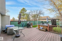 Wooden terrace with a fenced backyard, a hot tub, and grilling area - 