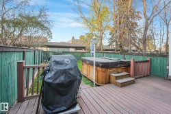 Deck featuring area for grilling, a fenced backyard, and a hot tub - 