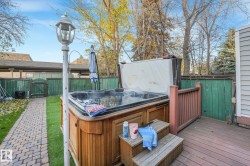 Wooden terrace featuring a hot tub and a gate - 