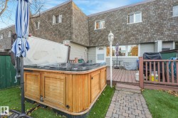 Rear view of property with a hot tub, a deck, mansard roof, and a shingled roof - 